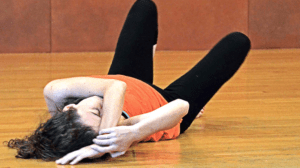woman lying down on the floor covering her face with hands