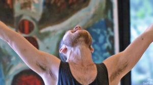 Natan Daskal extending arms in front of self-portrait drawing
